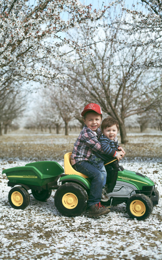 Two children in front of an almond orchard